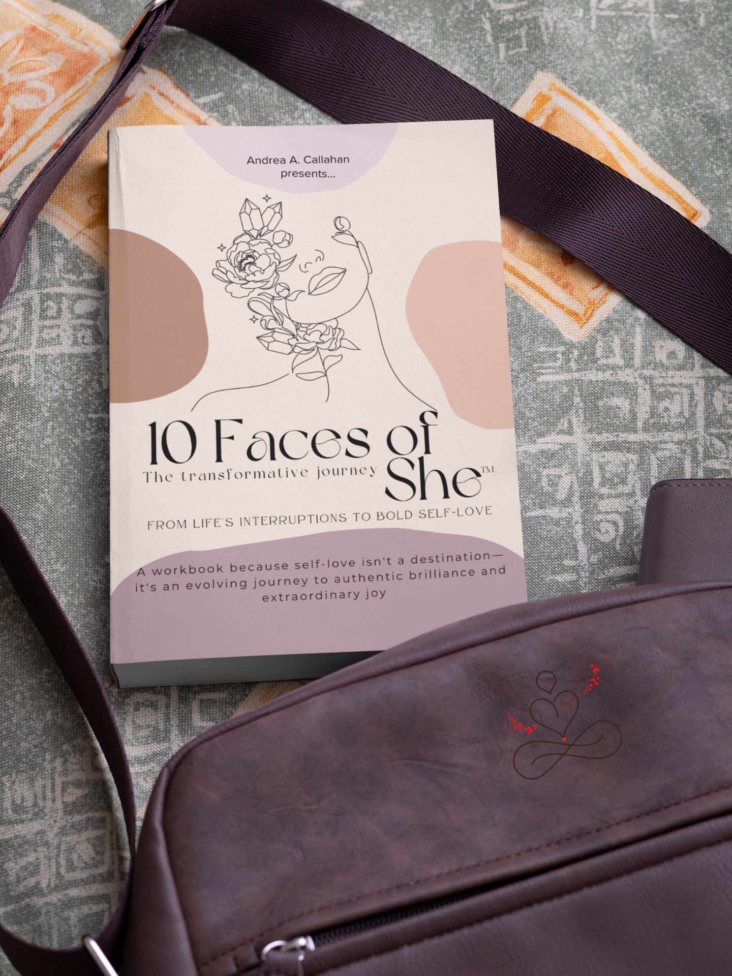 Andrea Callahan's 10 Faces of She™ The transformative journey book falling out of a leather 10 Faces of She bag